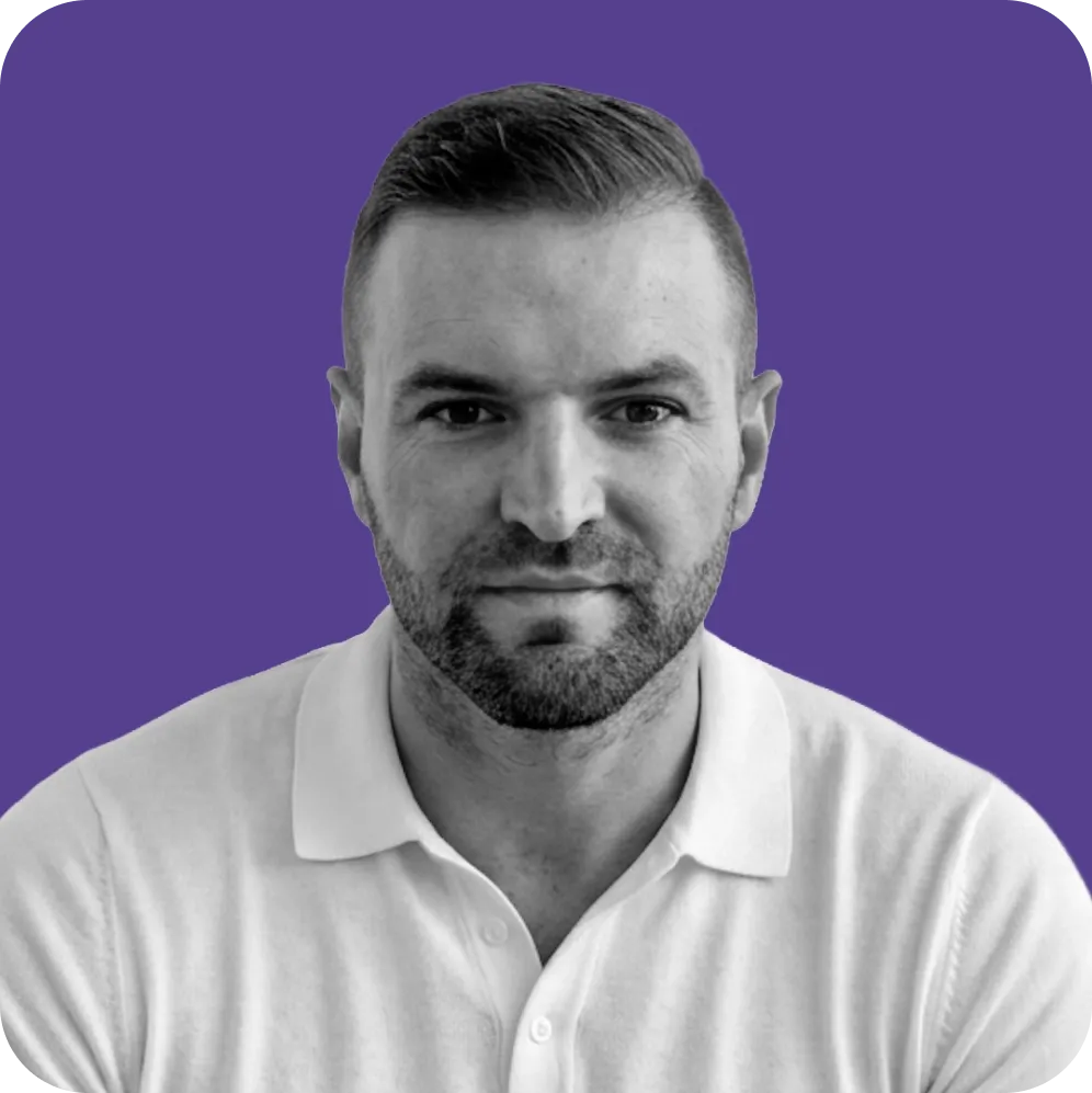 Man with beard in white polo shirt against a purple background.