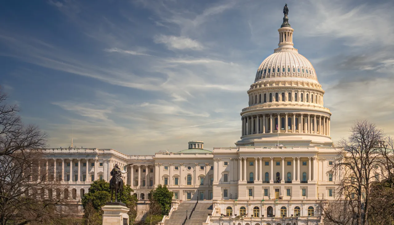 United States Capitol Building with its iconic dome under a partly cloudy blue sky.