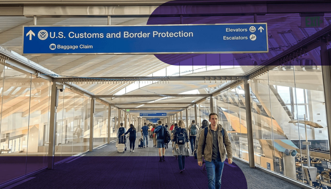 People walk through a bright airport walkway under a U.S. Customs and Border Protection sign.