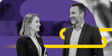 Smiling man and woman in business attire engaging in a friendly conversation.