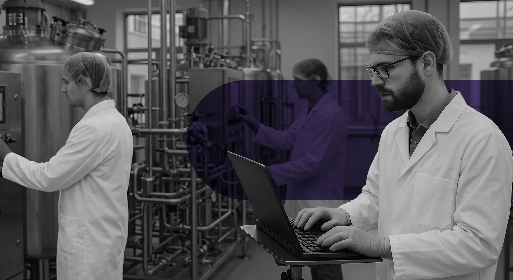 Two scientists in lab coats working with machinery and a laptop in a modern laboratory.
