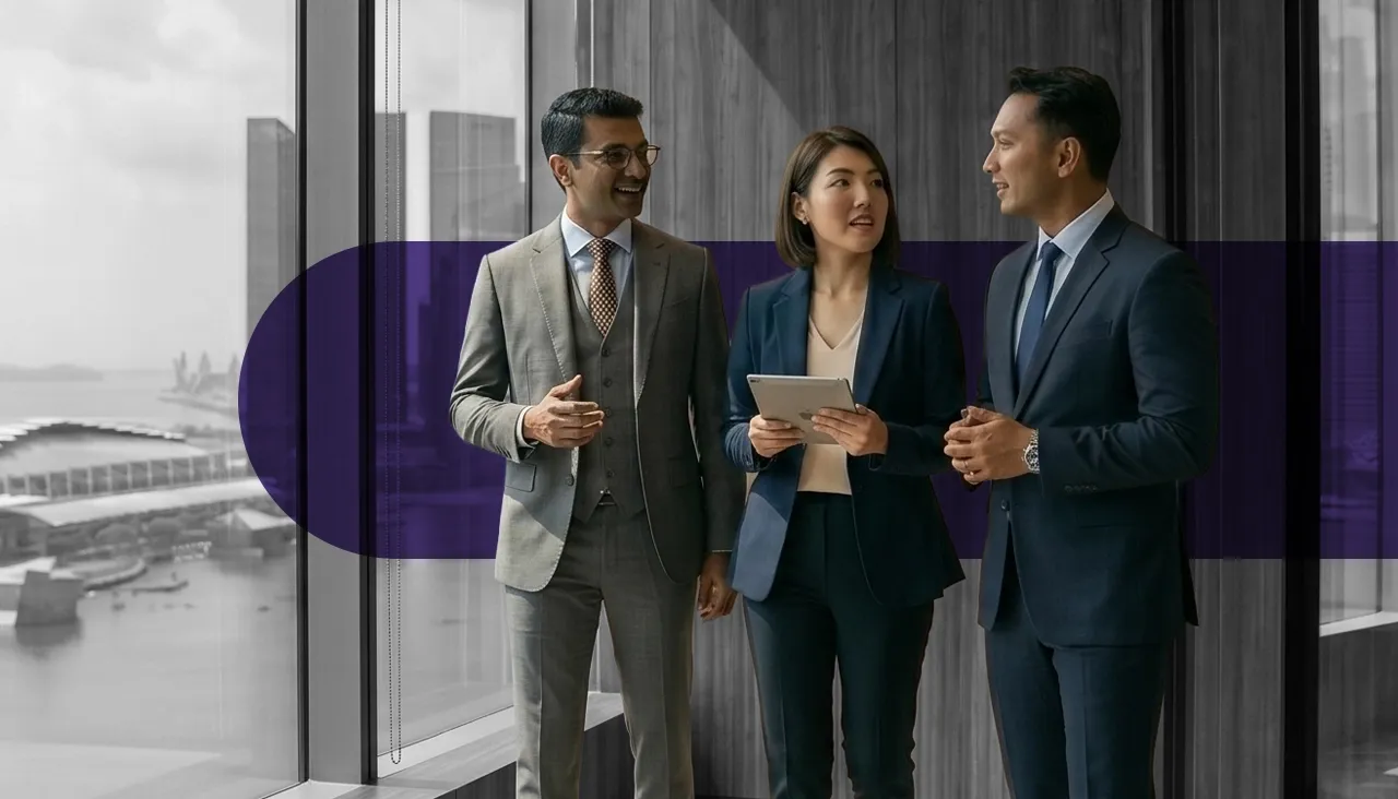 Three diverse business professionals discussing in a modern office with a city view.