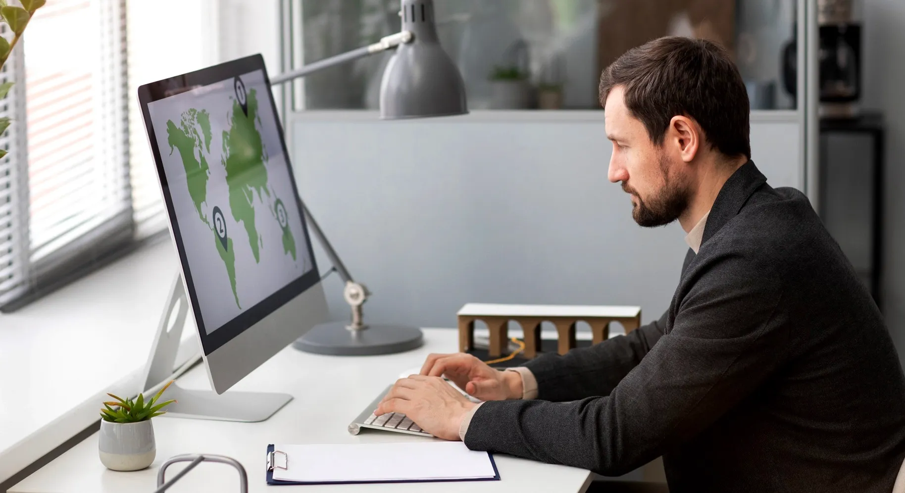 Professional working at a computer displaying a world map in a modern office