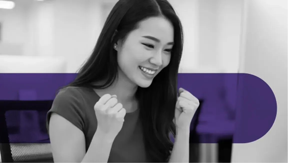 Joyful young Asian woman cheering with clenched fists, celebrating a success.