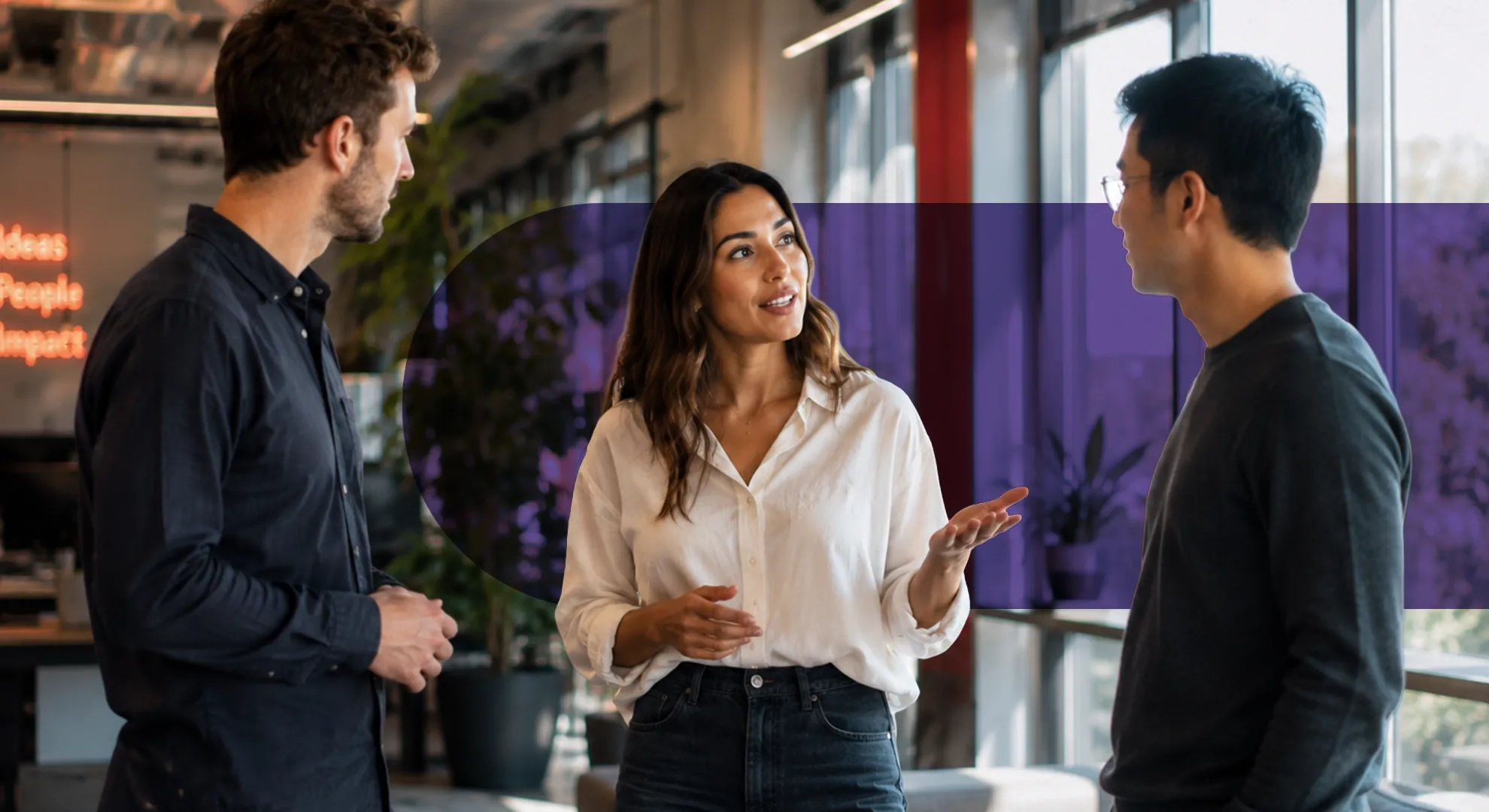 Three diverse colleagues, two men and one woman, discuss a project in a modern office.