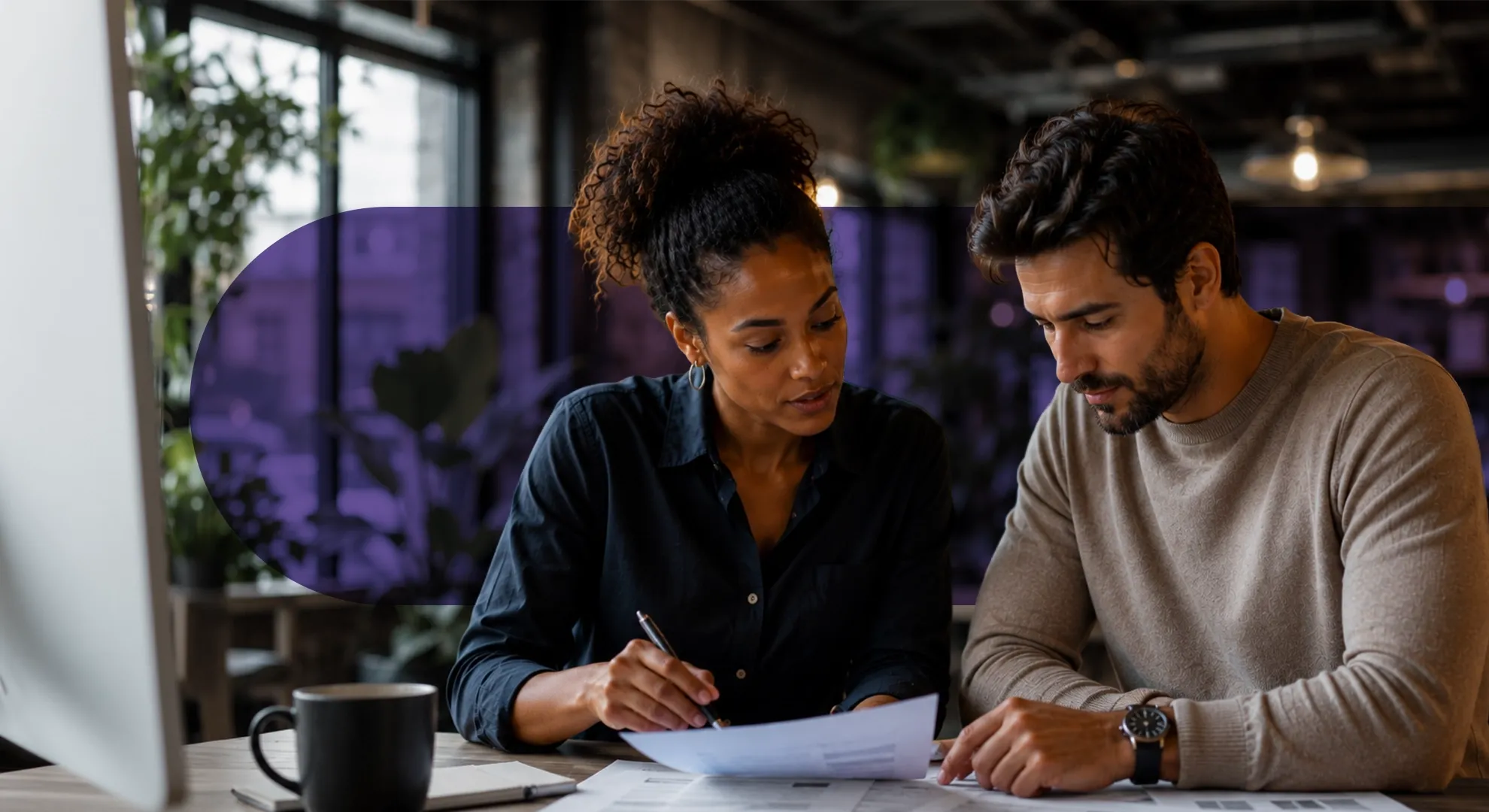 A man and a woman collaboratively review documents at a modern office desk.